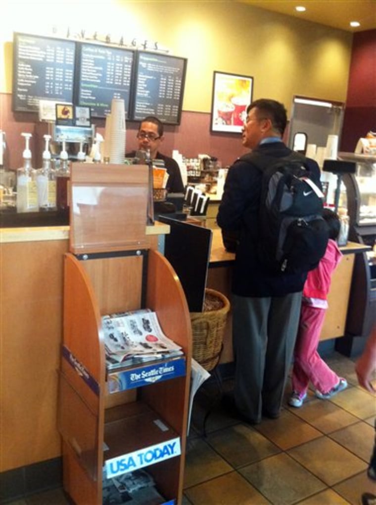 In this photo provided by ZhaoHui Tang, former Washington Gov. Gary Locke, who is the first Chinese-American ambassador to China, orders coffee Friday at Seattle Tacoma International Airport.